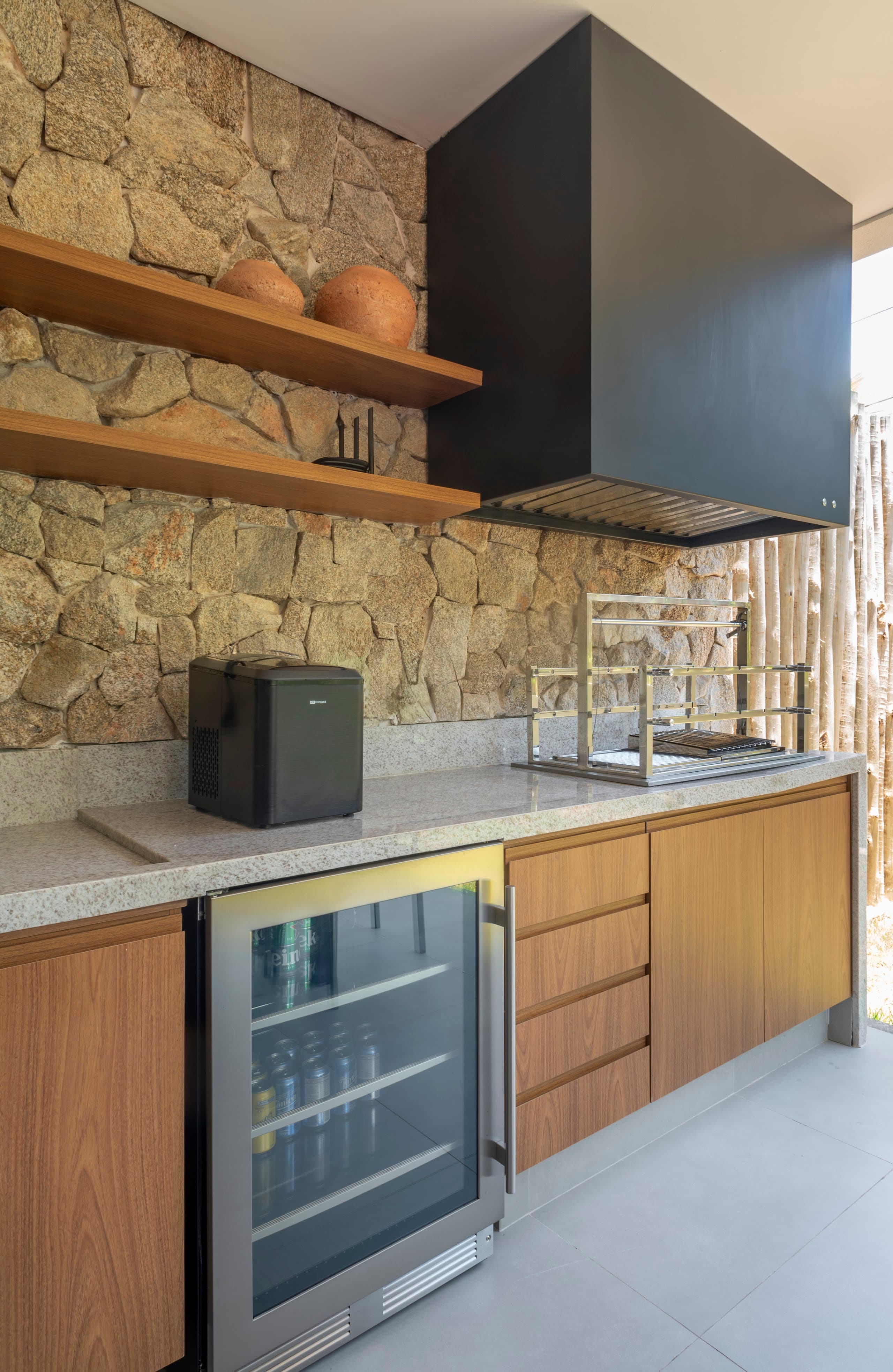Área gourmet com parede de pedra, marcenaria e adega